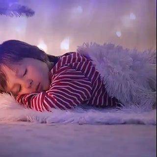 A sleeping child in red and white striped pajamas lying on fluffy white fabric.